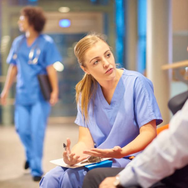 nurse chatting to patient in hospital corridor